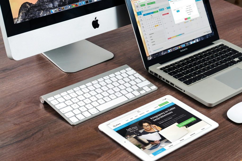 A sleek workspace featuring an Apple iMac, MacBook Pro, and an iPad displaying a responsive website, highlighting the importance of multi-device web accessibility in modern web development.