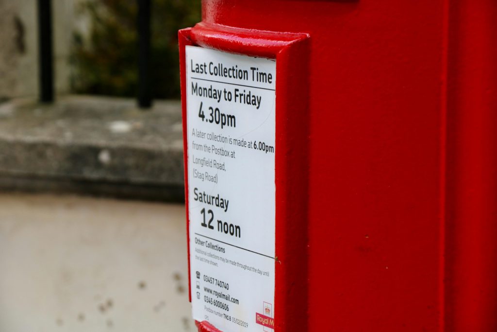 Close-up of a red Royal Mail postbox showing last collection times for letters in the UK
